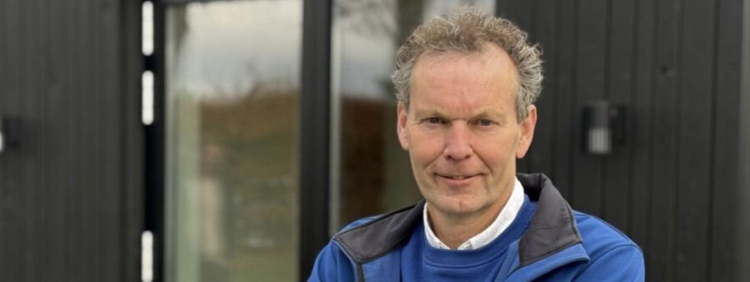 Mann steht vor moderner Fassade mit großen Glasflächen